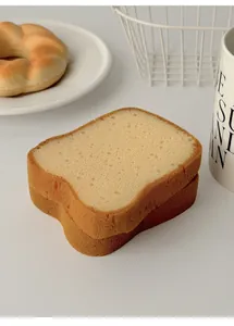 Detailed view of two toast-shaped kitchen sponges with realistic porous texture on a white plate