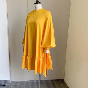 Detail view of bright yellow loose-fitting dress featuring lantern sleeves and ruffled hem
