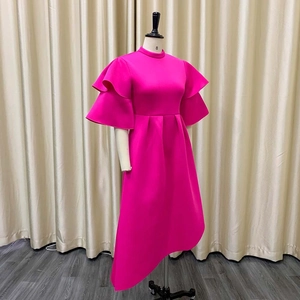 Detail of hot pink high-neck dress showing ruffle sleeves and high-low asymmetrical hem