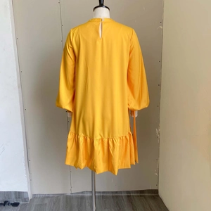 Close-up of yellow puff sleeve dress featuring a back neck slit and button closure