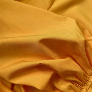 Detail of yellow woven fabric texture with twill weave and elegant ruched sewing accents