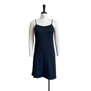 Detail of black camisole dress featuring thin straps and smooth satin-like fabric texture