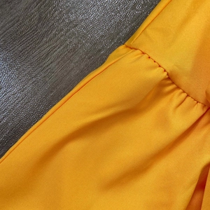 Detail view of vibrant yellow bubble sleeve dress featuring precise pleated seams and fabric texture