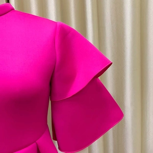 Detail of pink dress featuring double-layered ruffle sleeves and stand-up collar design