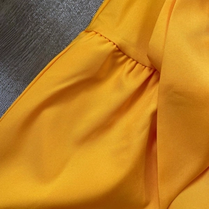 Detailed close-up of bright yellow fabric with pleated ruffles and neat stitching