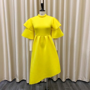 Detail of a bright yellow dress with layered ruffle cuffs and asymmetric pleated hem