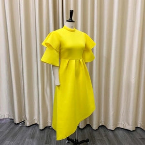 Detail of bright yellow evening dress with layered ruffle sleeves and asymmetric hemline