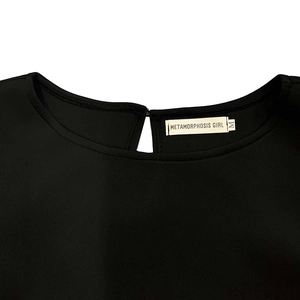 Détail de l'encolure d'une robe noire avec découpe en goutte et fermeture à bouton