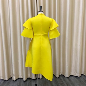 Detail view of yellow asymmetric dress featuring double ruffle sleeves and back zipper