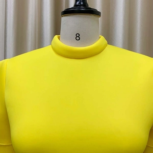 Detailed view of yellow dress with a structured high-collar neckline on a mannequin