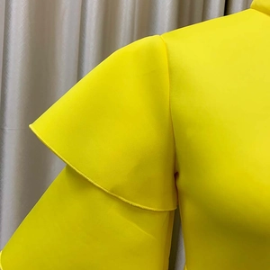 Detail of vibrant yellow tiered ruffle sleeves on a high-neck formal evening dress