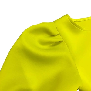 Détail de la robe vert néon avec manches bouffantes et plis aux épaules