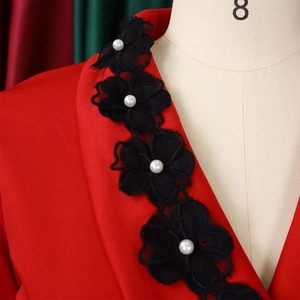 Detail of red V-neck dress featuring black lace flowers and pearl embellishments