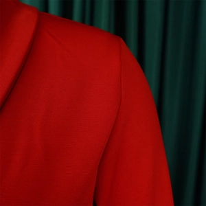 Detail of red V-neck dress fabric showing elegant shoulder seam and textured woven material