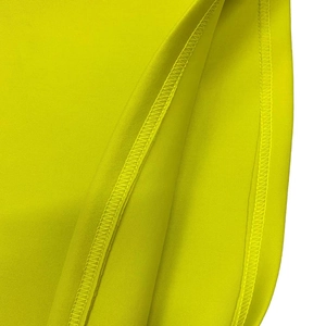 Gros plan détaillé montrant la couture surjet professionnelle sur un tissu en maille jaune