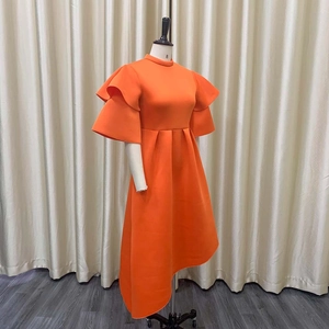 Detailed view of bright orange dress featuring a high collar and double ruffled sleeves