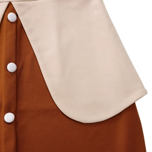 Détail d'une robe marron en maille avec bordure beige et boutons blancs décoratifs
