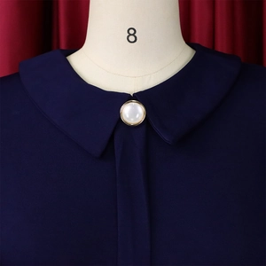Detail of navy blue dress featuring a Peter Pan collar and pearl button on a dress form