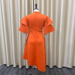 Detail view of double-layered ruffle sleeves and irregular hem on this orange dress