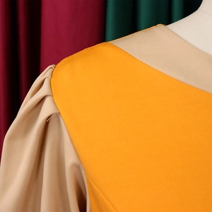 Detail of orange dress showing beige pleated bubble sleeves and neat stitching quality