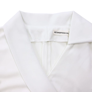 Gros plan du col en V d'une robe blanche avec texture de tissu tissé et étiquette de marque