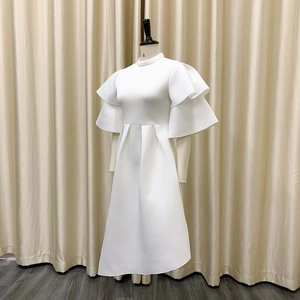 Detail of white dress featuring double layer ruffled sleeves and a high mock neckline