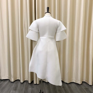 Rear view of white asymmetric dress showing double ruffled sleeves and hidden back zipper