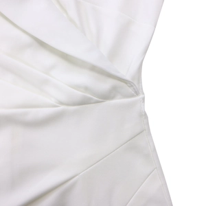 Détail de tissu tissé blanc avec des plis en V et des coutures précises sur la robe