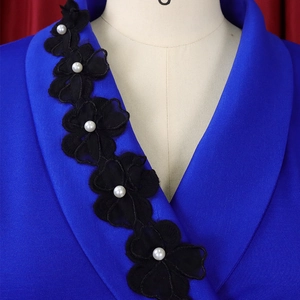 Detail of elegant navy V-neck dress with black lace floral patches and white pearls