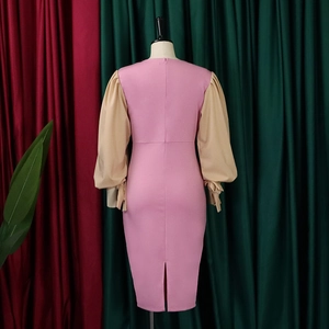 Detail of pink fitted dress with khaki lantern sleeves and bow tie cuffs on a mannequin