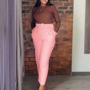 Pink high waisted dress pants with matching belt and tapered leg details on model