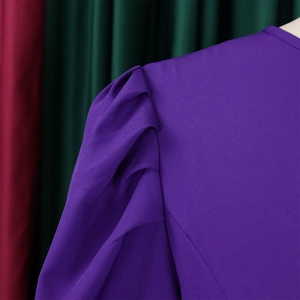 Dettaglio di abito viola con maniche a sbuffo strutturate e spalle plissettate