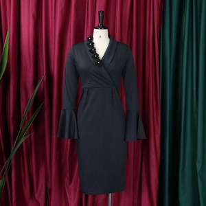 Detail of elegant V-neck dress with black floral applique and pearl accents on the collar