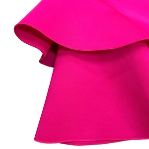 Detailed close-up of rose red ruffled hemline with professional overlock stitching finish