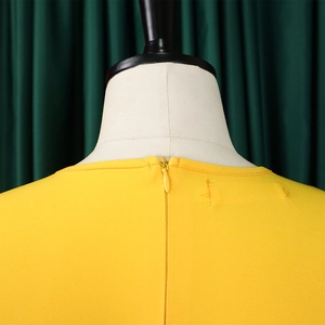 Dettaglio di un abito giallo brillante con cerniera invisibile sul retro su un manichino