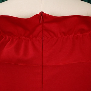 Détail de la robe rouge à épaules dénudées avec fermeture éclair invisible et volants