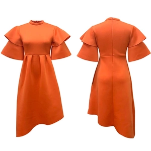 Detail of high neck orange dress with tiered ruffle sleeves and asymmetric hemline