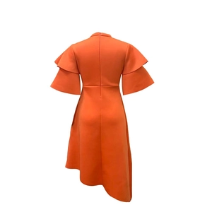 Detail view of the orange dress featuring ruffles and a concealed zipper closure