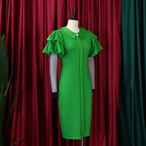 Detail view of green dress featuring mesh sleeves with black polka dots and ruffles