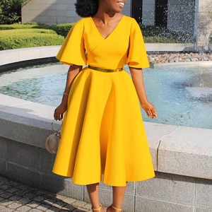 Detailed view of yellow V-neck dress with flare sleeves and gold belt in a sunny square