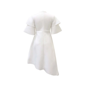 Detail of white dress featuring layered ruffle sleeves and an asymmetric irregular hem