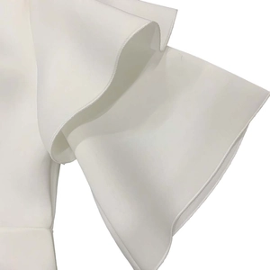 Detailed view of elegant white tiered ruffle sleeve design on high-neck party dress