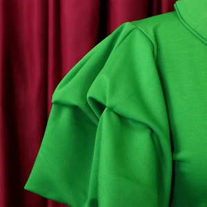 Detailed macro view of vibrant green dress featuring layered puff sleeves and pleated fabric