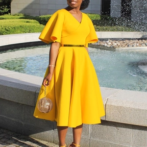Close-up of bright yellow V-neck dress featuring bell sleeves and a gold metal belt