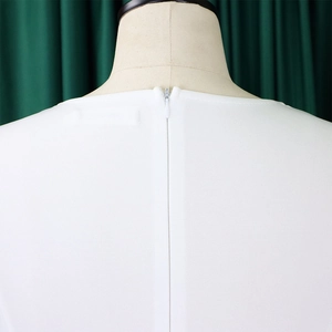 Détail de l'encolure d'une robe blanche avec une fermeture éclair invisible au dos
