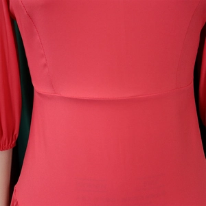 Dettaglio del vestito rosso con cucitura in vita a pieghe e finiture sartoriali curate