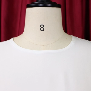 Dettaglio di un vestito bianco a girocollo con cuciture rifinite su un manichino beige