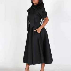 Détail de la robe noire évasée avec manches bouffantes et grand nœud élégant au col
