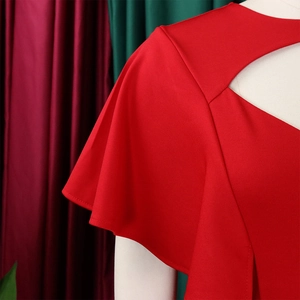 Détail de robe rouge avec découpe géométrique au décolleté et manches courtes volantées