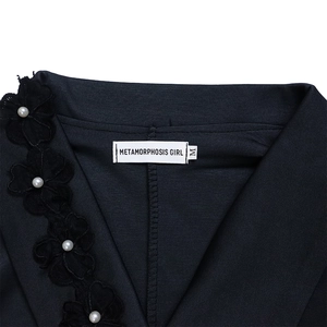 Detailed view of elegant black V-neck dress with 3D fabric flowers and pearl accents